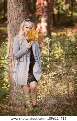 A young, blonde woman walking through the forest on a sunny autumn day.