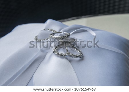 Wedding rings pictured on a white ornamental pillow