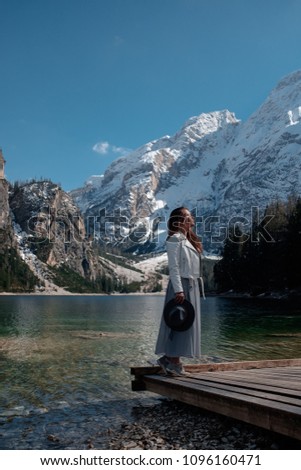 A beautiful girl stands on the shore of a lake in the Dolomites.  Braies lake. Life style blogger