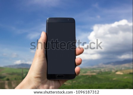Hand holding smart phone mock up over beautiful countryside landscape background