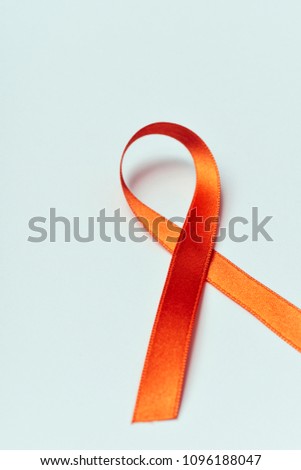 an orange ribbon, for multiple sclerosis awareness, on an off-white background with some blank space around it Royalty-Free Stock Photo #1096188047