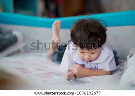 Asian Chinese girl playing smartphone on bed, watching smartphone, kid use phone and play game, child use mobile, addicted game and cartoon
