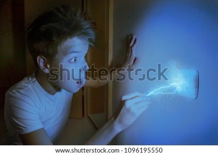 Electric lightning bolt strikes a boy, who is touching wall plug. Be careful and cautious, electricity is dangerous. Voltage and Current concept Royalty-Free Stock Photo #1096195550