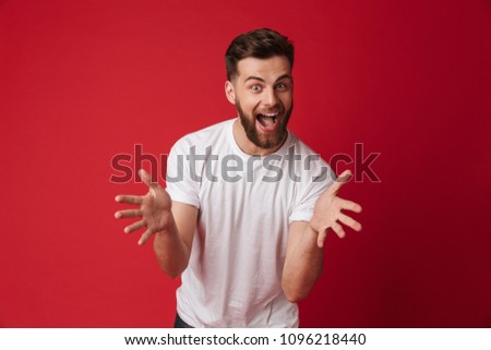 Picture of excited screaming young handsome man standing isolated over red wall background. Looking camera.