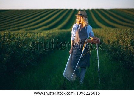 Woman artist painting with oil paints in a field