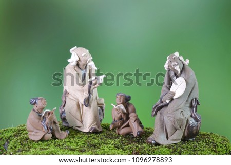 Learn Chinese language concepts : Clay sculptures of Confucius with students reading book. Selective focus, blurred background with copy space