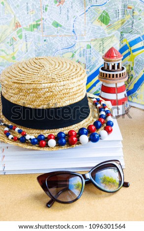 Straw hat, beads, ceramic lighthouse against map