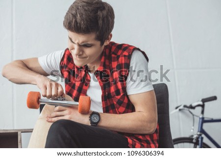 young skater repairing his longboard at home