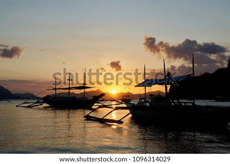 wooden fisher boats with an orange sunset in the background