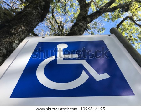 Sign plate for disabled parking space, with a background with trees.
