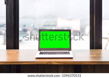 Green screen of Mockup image of laptop with blank screen on wooden table.