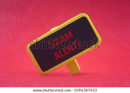 wooden clip written scam alert over red background