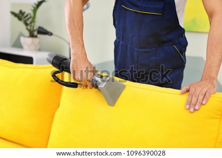 Dry cleaning worker removing dirt from sofa indoors Royalty-Free Stock Photo #1096390028