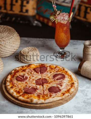 sliced hot pizza with salami sausages with a glass of natural juice