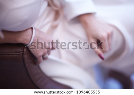 a bracelet on the hand of a sitting girl in a light attire. background blur.