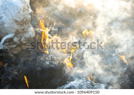 Soft flame fire and smog is burning garbage or waste  on dark background. Incineration of waste causes air pollution and global warming. Flames are reddish orange depending on the type of fuel.