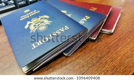 Red and blue passport are placed on a wooden table.