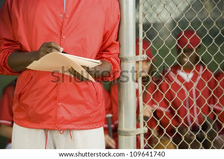 Midsection of a man holding the scorecard of his team with players sitting in background