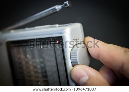 Portable radio (FM and shortwave); man's hand on tuning dial. Royalty-Free Stock Photo #1096471037