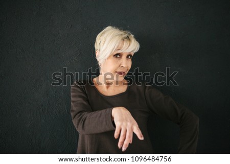 Mature stylish woman shows gestures how cool she is. A conceptual photo of how the old generation wants to be modern.