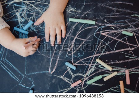 Close-up of child hand draws on chalkboard, top view