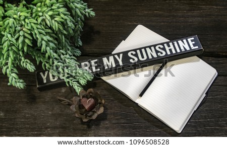 Opened notebook with a "you are my sunshine" sign on the table