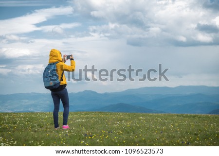 Girl taking photos with cellphone in nature.