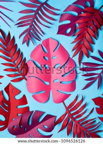 Bright tropical paper leaves on pastel blue background. Summer concept. Flat lay.