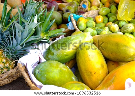 Papayas and pineapples in a basket in a market in South America.