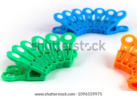 Multicolored plastic clothespins, arranged in groups on a white background.