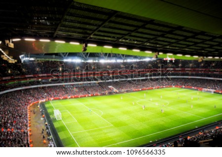 Blurred background of football players playing and soccer fans in match day on beautiful green field with sport light at the stadium.Sports,Athlete,People Concept.Arsenal,Emirates Stadium. Royalty-Free Stock Photo #1096566335