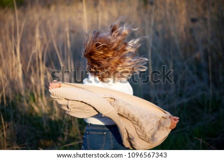 Girl is running out. Young woman in the field, feel freedom and happiness. Casual style. Back view