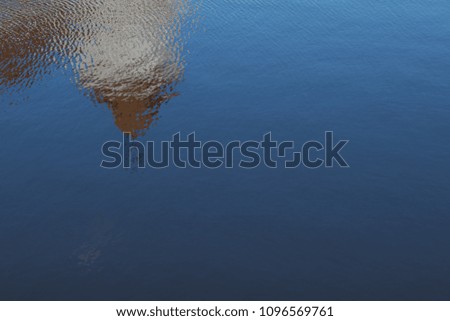 Texture background of water and shallow waves. Reflections of the building in the water.