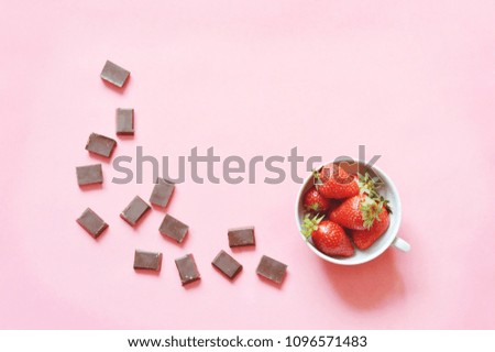Strawberries in a cup and slices of dark chocolate on a pink background. Delicious and exquisite dessert. Flat lay photo cafe table