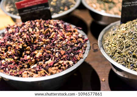 Closeup of apricot herbal tea spices on display in metal bowl tray filled with fruit and berry mix, sign, green herbs