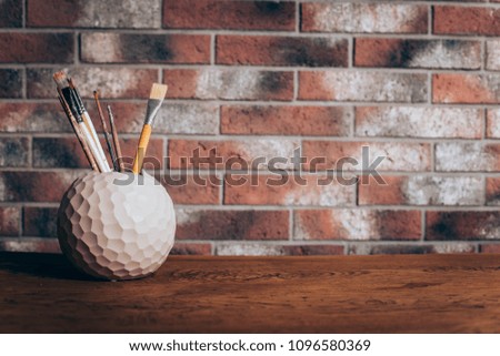 
Brushes for painting on a brick wall background on a wooden table. a concept for an art school.