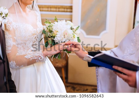 Newlyweds stand before the priest on a wedding ceremony and exchange the rings