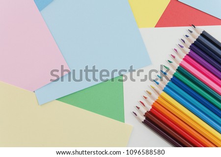 Colorful pencils lying on colorful cardboard sheets