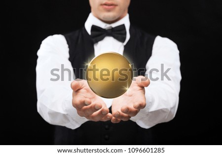 currency, finances and business concept - close up of magician with blank golden coin making trick over black background
