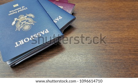 Red and blue passport are placed on a wooden table.