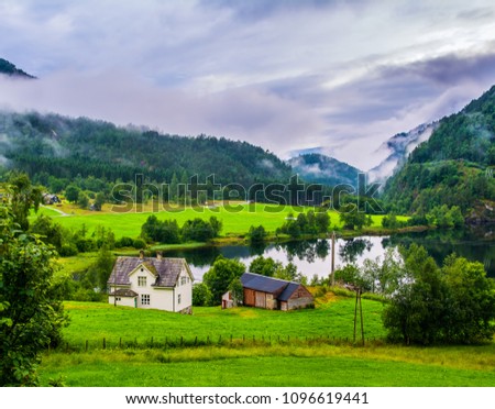 Typical countryside Norwegian landscape with houses on the shore of the lake. Cloudy summer morning in Norway, Europe. Artistic picture. Beauty world.