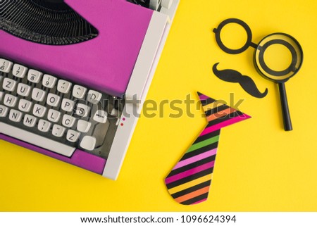 Flat lay of vintage pink typewriter and paper props in form of retro hipster man with magnifying glass on yellow background minimal creative concept.