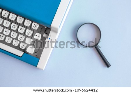 Flat lay of vintage typewriter in blue color and magnifying glass minimal creative concept.