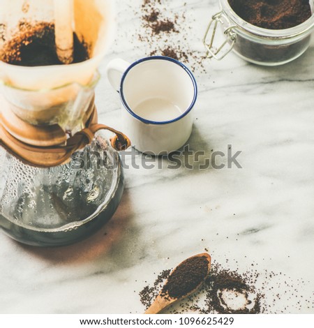 Morning black filtered coffee in flask, white cup and coffee in jar on light grey marble table background, copy space, square crop. Alternative coffee brewing concept