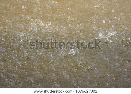 Heavy rain falls on the surface of the flood. Rain spray splashes into small waves on the surface.
