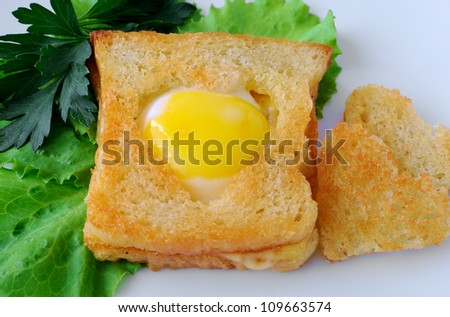 Toast with egg in the form of a heart on a platter with lettuce leaves
