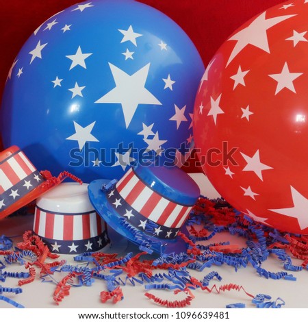 Closeup of three novelty small party hats decorated patriotically with the Stars and Stripes in confetti with one red and one blue balloons in the background both decorated with white stars.