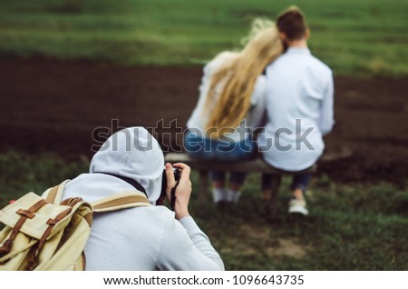 Teenagers , brother and sister. The relationship between people in the family . Dressed in a white shirt and jeans. a photographer takes pictures of couple