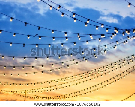 Sunset scene of light bulbs on string wire Royalty-Free Stock Photo #1096658102