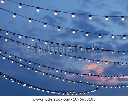 Sunset scene of light bulbs on string wire Royalty-Free Stock Photo #1096658105
